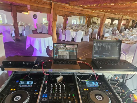 DJ-Pult mit Playern, Mischpult und zwei Laptops vor dem Veranstaltungsraum