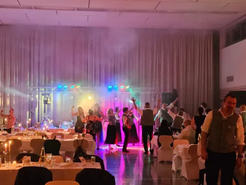 Saal mit violetter Lichtstimmung und Tanzfläche
